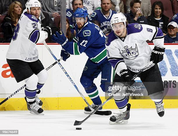 Jarret Stoll of the Los Angeles Kings and Daniel Sedin of the Vancouver Canucks look on as Drew Doughty of the Los Angeles Kings skates up ice with...