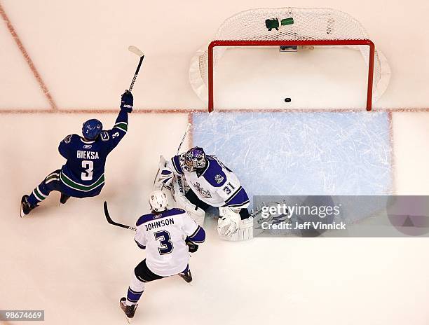 Jack Johnson and Erik Ersberg of the Los Angeles Kings look on as Kevin Bieksa of the Vancouver Canucks watches a Canuck shot get into the net in...