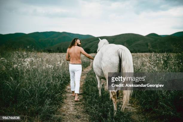 männliches pferdetrainer führt sein pferd durch wiese - beautiful male feet stock-fotos und bilder
