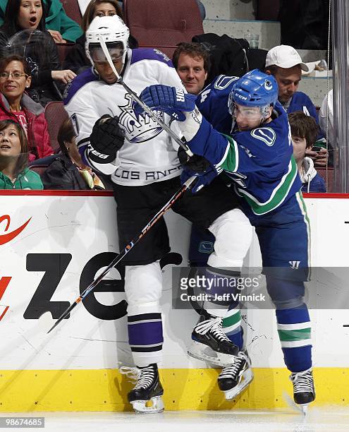 Wayne Simmonds of the Los Angeles Kings is checked into the boards by Alex Burrows of the Vancouver Canucks in Game Five of the Western Conference...