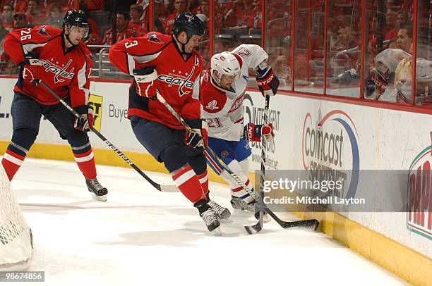 Tom Poti of the Washington Capitals trys to contol the puck against Brian Gionta of the Montreal Canadiens during Game Two of the Eastern Conference...