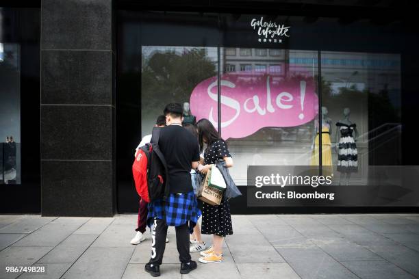 Pedestrians and shoppers stand in front of a Galeries Lafayette SA department store on Wangfujing Street in Beijing, China, on Wednesday, June 27,...