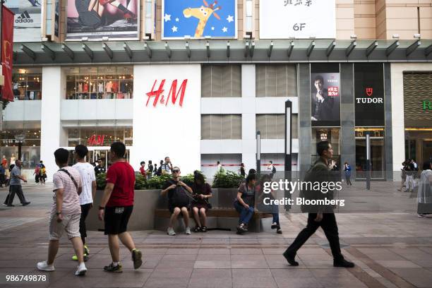 Pedestrians and shoppers walk past a Hennes & Mauritz AB store on Wangfujing Street in Beijing, China, on Wednesday, June 27, 2018. Consumer...