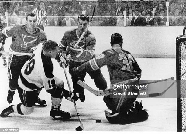 Bill Masterton of the Minnesota North Stars takes a shot that is blocked by goalie Seth Martin as Martin's teammates Bob Plager and Fred Hucul move...