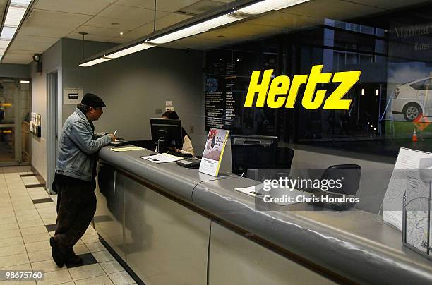 Man stands at the counter of a Hertz car rental location April 26, 2010 in New York City. Hertz Global Holdings Inc. Has announced that it will buy...