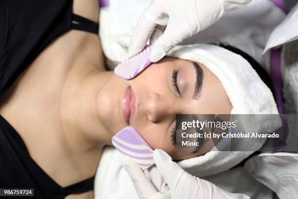 aesthetic doctor performs face cleansing on young patient - carabobo stock-fotos und bilder