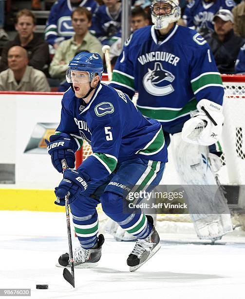 Roberto Luongo of the Vancouver Canucks looks on as Christian Ehrhoff of the Vancouver Canucks skates up ice with the puck in Game Five of the...