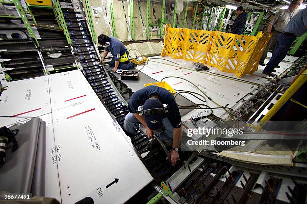 John Doaz, top, and Darrell Kluin use vacuum units to catch debris as holes are drilled through two connecting composite sections of a Boeing Co. 787...