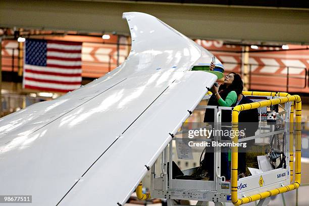 Employees work on the wing of a Boeing Co. 787 Dreamliner aircraft is attached during final assembly in Everett, Washington, U.S., on Tuesday, March...