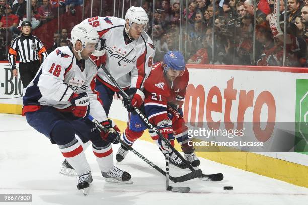 Tyler Sloan of the Washington Capitals and teammate Eric Belanger battle for the puck with Brian Gionta of Montreal Canadiens in Game Four of the...
