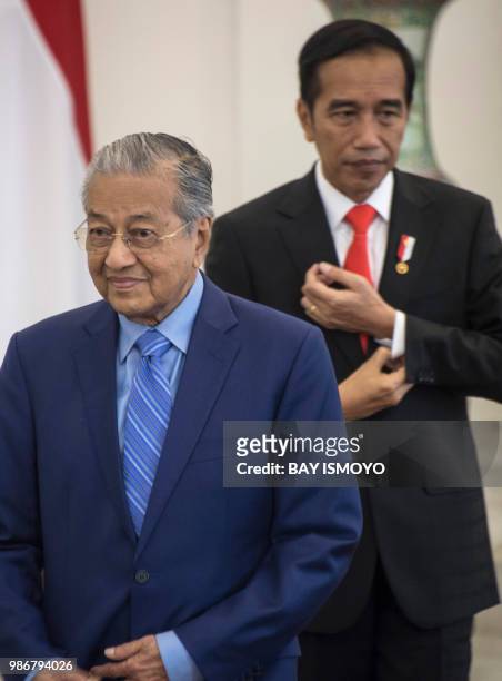 Indonesia's President Joko Widodo and Malaysia's Prime Minister Mahathir Mohamad walk together before a joint press conference at the presidential...