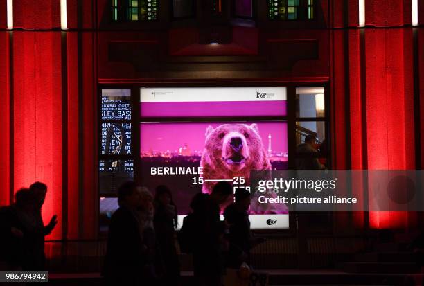 February 2018, Germany, Berlin: Passer-bys pass a billboard of the Berlinale film festival at the illuminated Friedrichstadt-Palast. Photo: Jens...