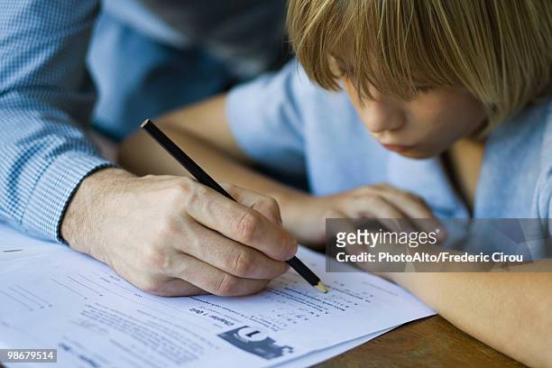 male junior high student watches as teacher corrects assignment, close-up - teacher bending over stock-fotos und bilder