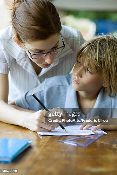 teacher correcting student's classwork, student looking up at teacher - teacher bending over stock-fotos und bilder