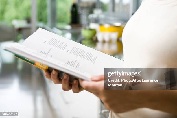 reading recipe in cookbook - cookbook stock pictures, royalty-free photos & images