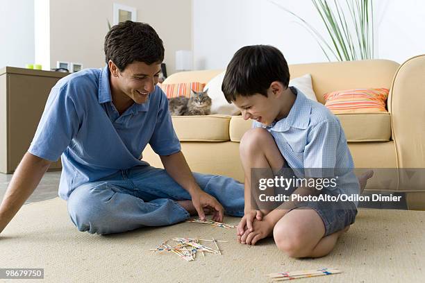 father and son playing pick up sticks - mikado stock pictures, royalty-free photos & images