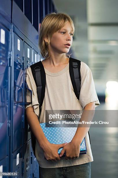 junior high student leaning against locker in school corridor - junior high foto e immagini stock