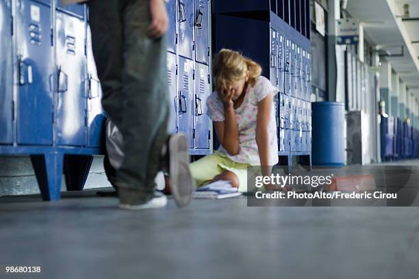 junior high student sitting on floor crying, boy standing by watching - acoso escolar fotografías e imágenes de stock