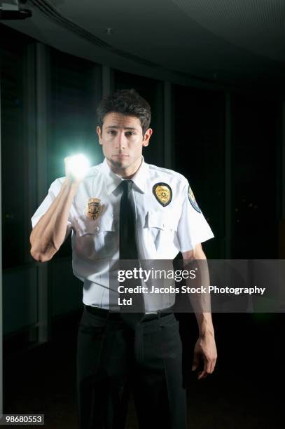 hispanic security guard checking dark offices - lampe de poche photos et images de collection