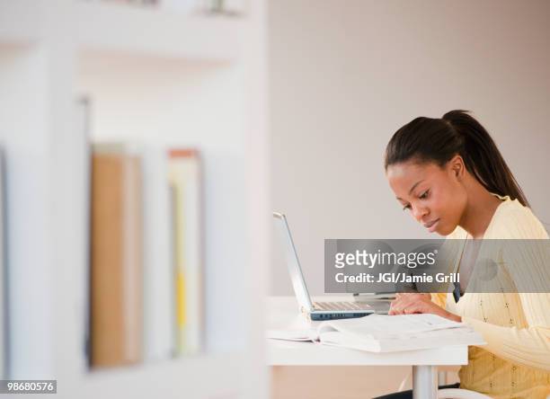 mixed race woman doing homework with laptop - person in further education ストックフォトと画像