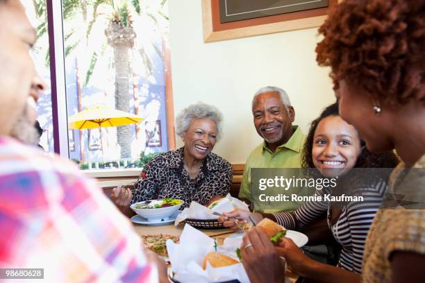 african american family eating in restaurant - girls laughing eating sandwich stock-fotos und bilder