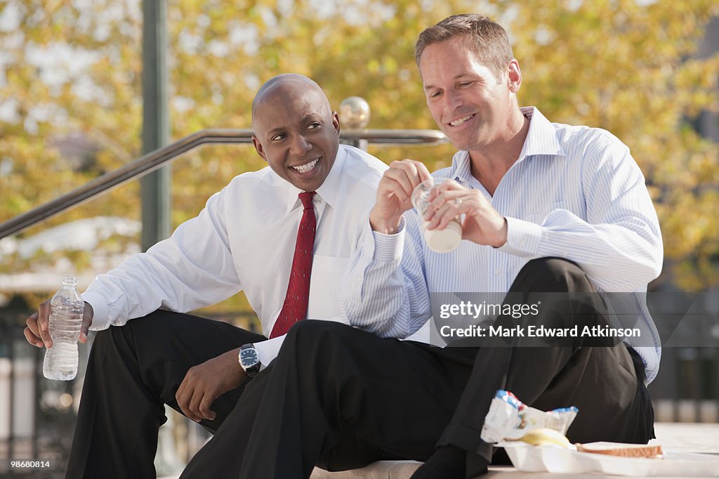 Businessmen eating lunch on steps