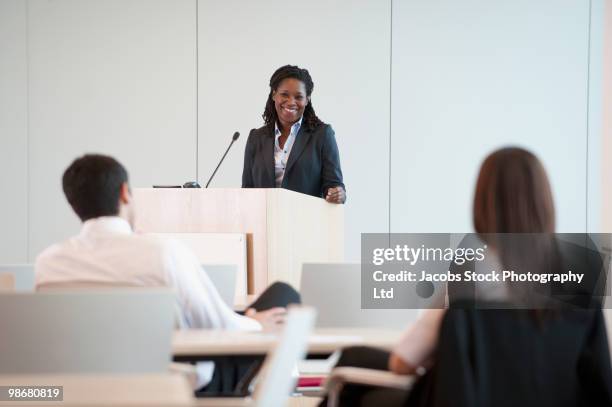 black businesswoman speaking at podium - woman presenter stock pictures, royalty-free photos & images