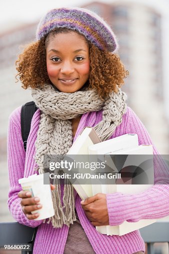 Mixed race woman holding books and drinking coffee Mixed race woman holding books and drinking coffee