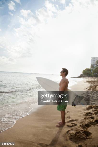 japanese man holding surfboard on beach - inti st clair stock pictures, royalty-free photos & images