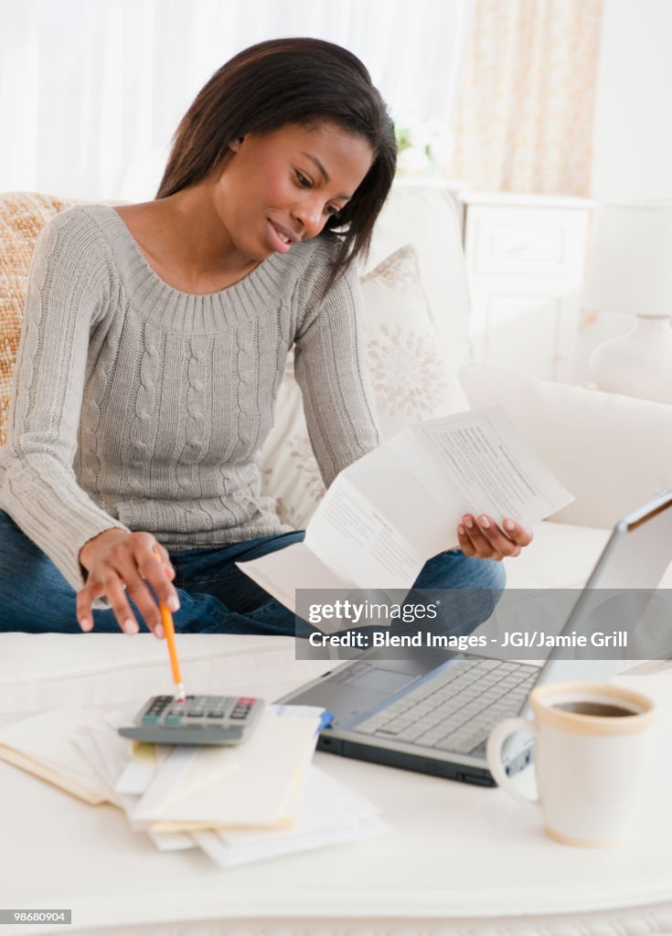 Mixed race woman paying bills in living room