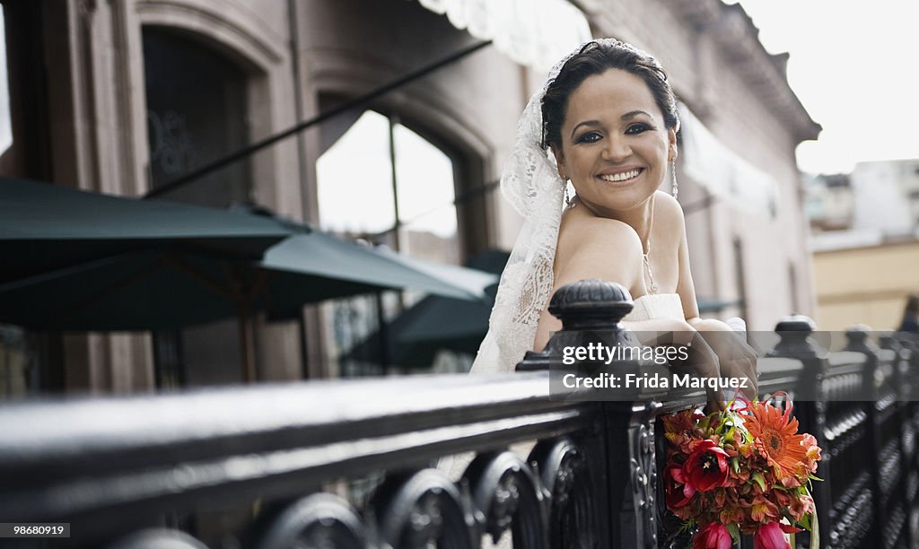 Hispanic bride on balcony smiling