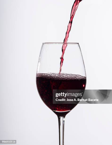 red wine splashing in glass in front of white background - kurzzeitfotografie stock-fotos und bilder