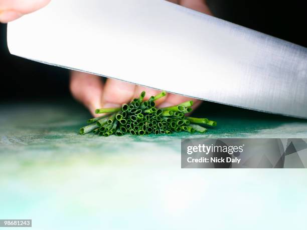 close up of a knife cutting chives - affettare foto e immagini stock