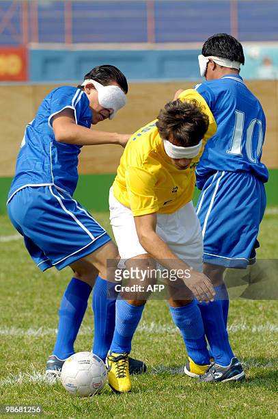 Brazilian blind footballer Damio Ramos vies the ball with Salvadorean blind footballers Esau Escobar and Mauricio Bonifacio , during a match at Jorge...