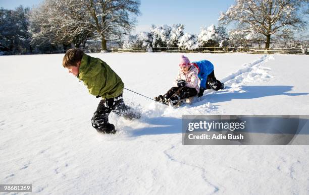 children playing on sledge in the snow - pulling sledge stock pictures, royalty-free photos & images