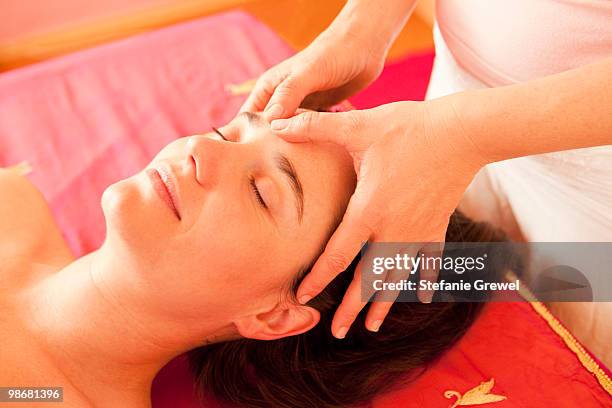 woman getting a facial massage - dießen stock-fotos und bilder