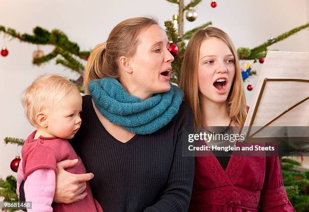 mother, daughter, baby singing carols - carol singer stock pictures, royalty-free photos & images