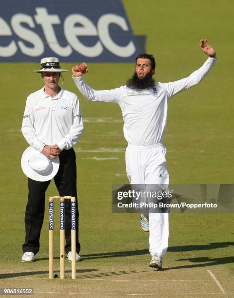 Moeen Ali of England bowls past umpire Billy Bowden during the 1st Test match between England and Sri Lanka at Lord's Cricket Ground, London, 13th...