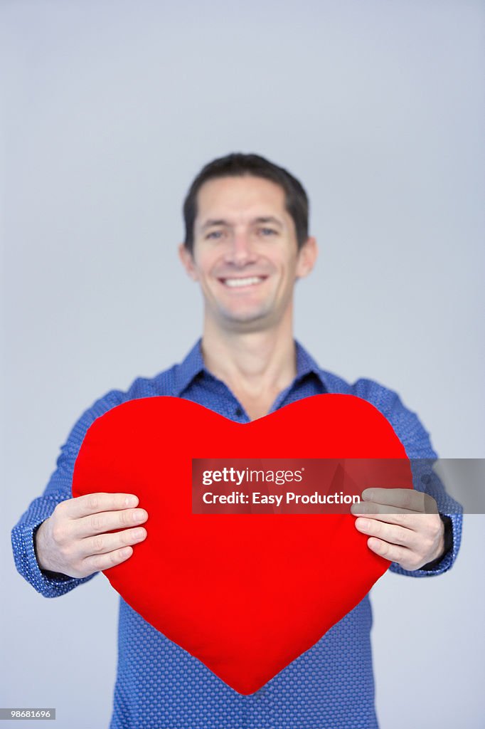 Smiling man showing a big red heart