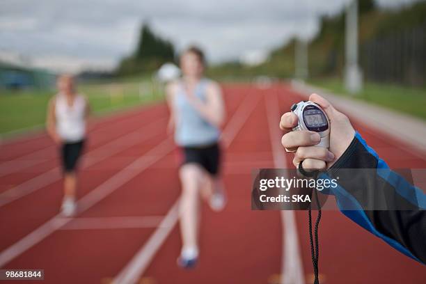 2 female athletes and stopwatch - arm span stockfoto's en -beelden