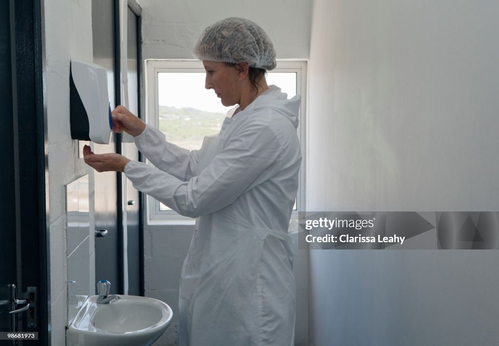 Factory worker using soap dispenser