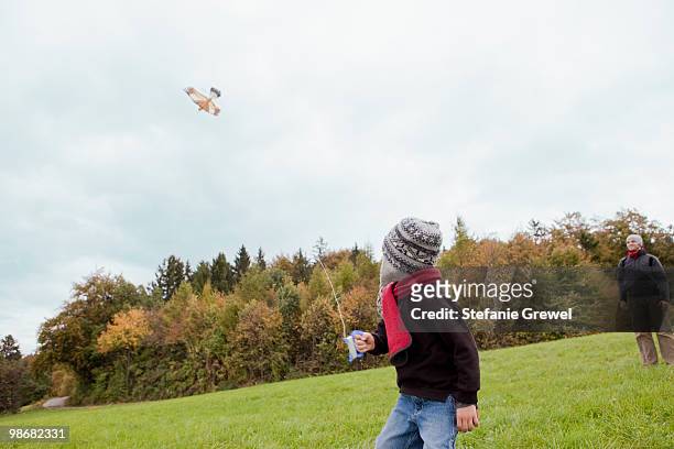 father watching son flying a kite - stefanie grewel 個照片及圖片檔