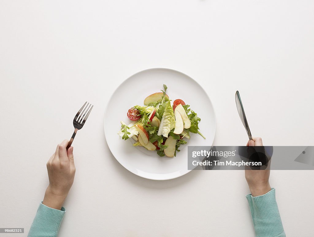 Hands by a plate of salad