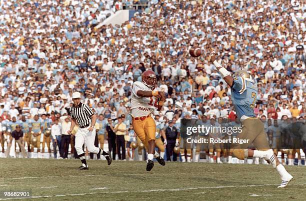 Rodney Peete of the USC Trojans passes against Chance Johnson of the UCLA Bruins at the Rose Bowl on November 19, 1988 in Pasadena, California.