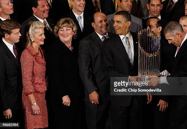 President Barack Obama reacts to a comment from a guest while holding the Major League Baseball Commissioner's Trophy and posing for photographs with...