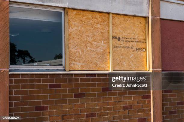 boarded up smashed windows on a school building - johnfscott stock pictures, royalty-free photos & images