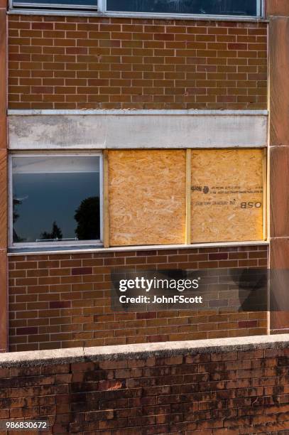 boarded up smashed windows on a school building - johnfscott stock pictures, royalty-free photos & images