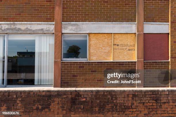 boarded up smashed windows on a school building - johnfscott stock pictures, royalty-free photos & images