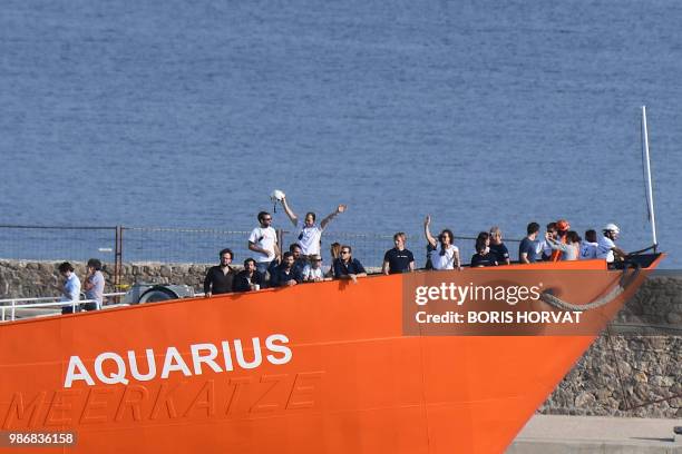 People wave aboard the Aquarius rescue vessel, chartered by French NGO SOS-Mediterranee and Doctors Without Borders , as the ship arrives at the...