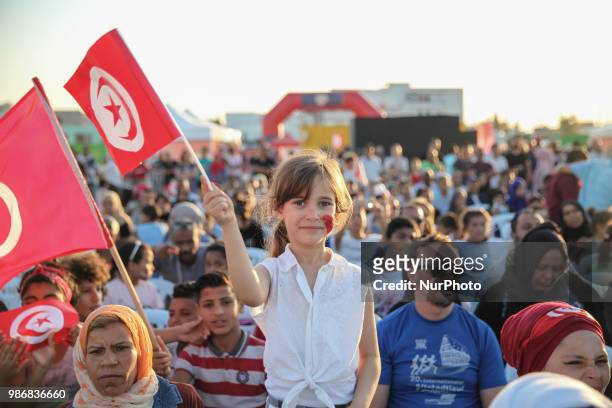 Little girl waves the flag of Tunisia as she attends a public viewing held in Mellassine, a popular neighbourhood of the capital Tunis located near...